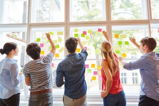 Group of people putting sticky notes on a window front