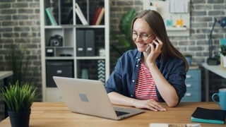Woman using laptop while on phone